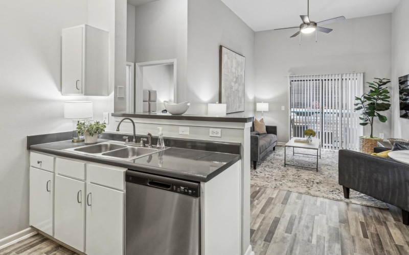 a kitchen with white cabinets connected to a living room