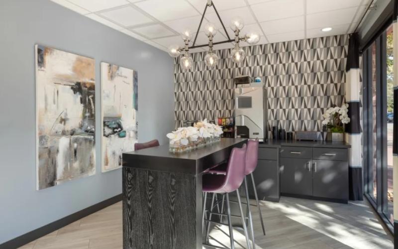 a bar table with pink stools and a coffee bar